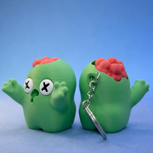 Two green zombie bean fidgets side by side - a standalone figurine and a keyring version